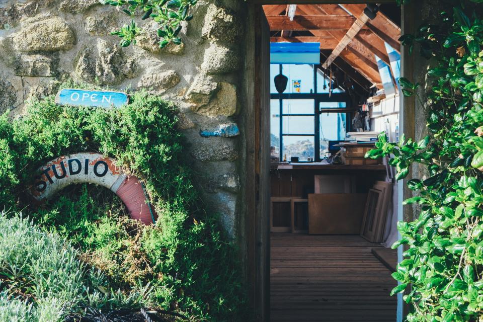 house home shack cabin workshop studio wood beams frames tools windows door stone walls plants ivy vegetation life ring preserver float buoy open sign shop