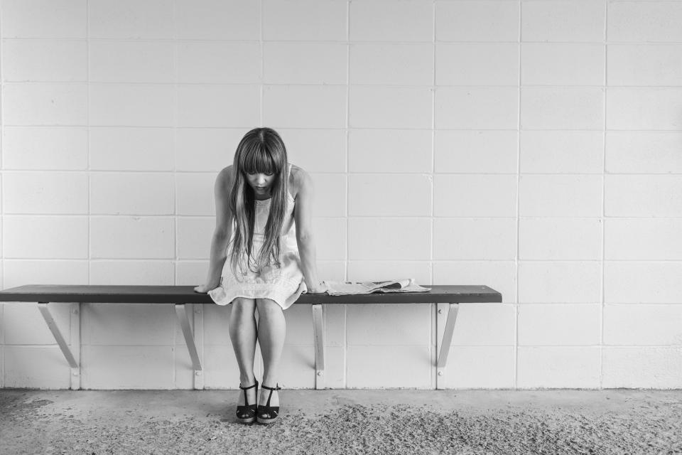 girl, woman, people, brunette, long hair, dress, legs, feet, shoes, bench, sitting, newspaper, concrete, wall, sad