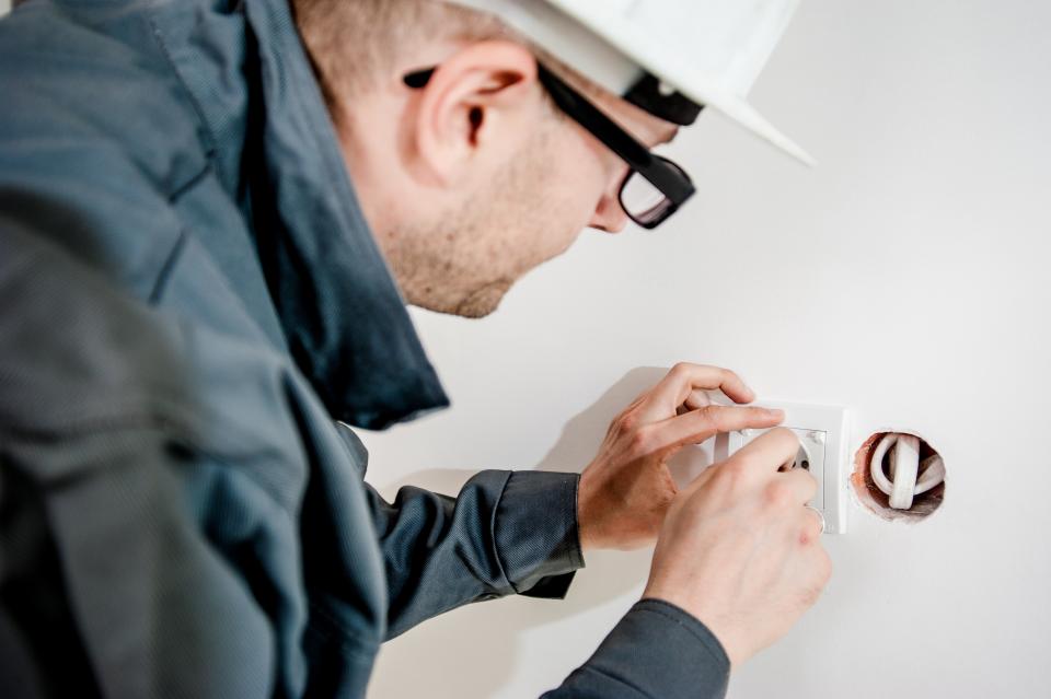 electrician electricity outlet power plug socket wires wall repairs construction worker guy man people safety glasses hard hat house home