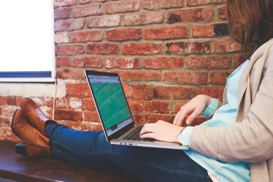 macbook laptop computer technology girl woman people working business creative design typing bricks wall bench startup office heels jeans internet