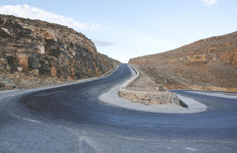 winding road rocks dirt sky pavement rural countryside